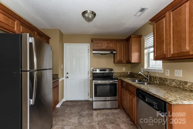 a kitchen with stainless steel appliances granite countertop a refrigerator stove and sink