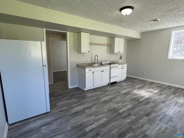 a kitchen with granite countertop a stove a refrigerator and a sink