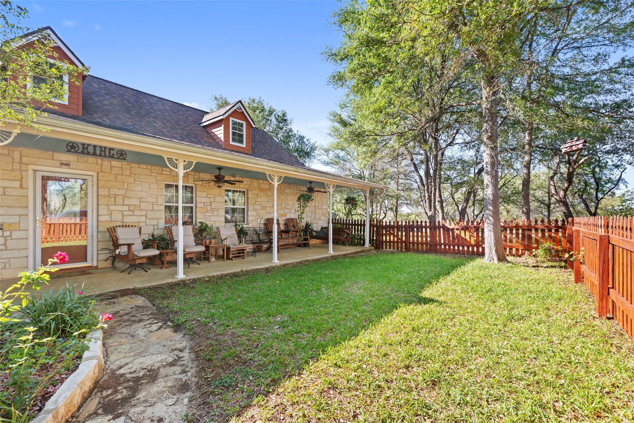 399 Upper Elgin River Road Elgin, TX 78621 - Photo 28 of 39 Rear view of house with stone siding, ceiling fan, a porch, roof with shingles, and a fenced backyard