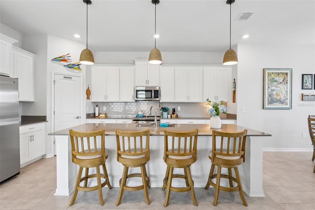 6049 Claystone Way Mount Dora, FL 32757 - Photo 12 of 55 a kitchen with stainless steel appliances kitchen island granite countertop a dining table chairs and white cabinets