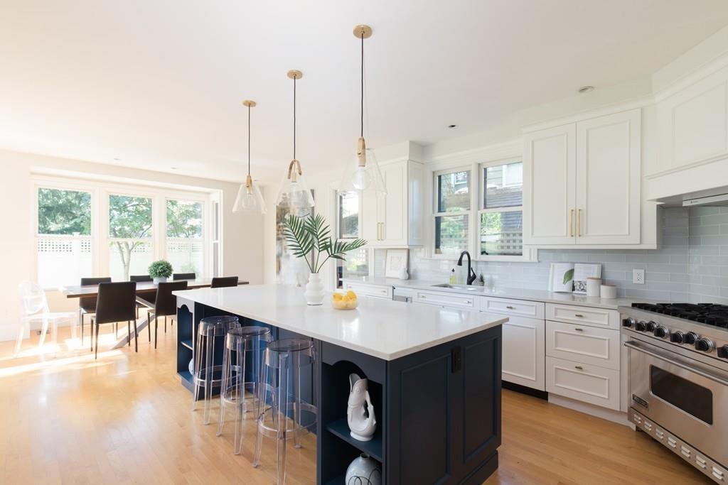 11 Channing Street Cambridge, MA 02138 - Photo 2 of 14 a kitchen with stainless steel appliances granite countertop a stove a sink dishwasher and a dining table with wooden floor