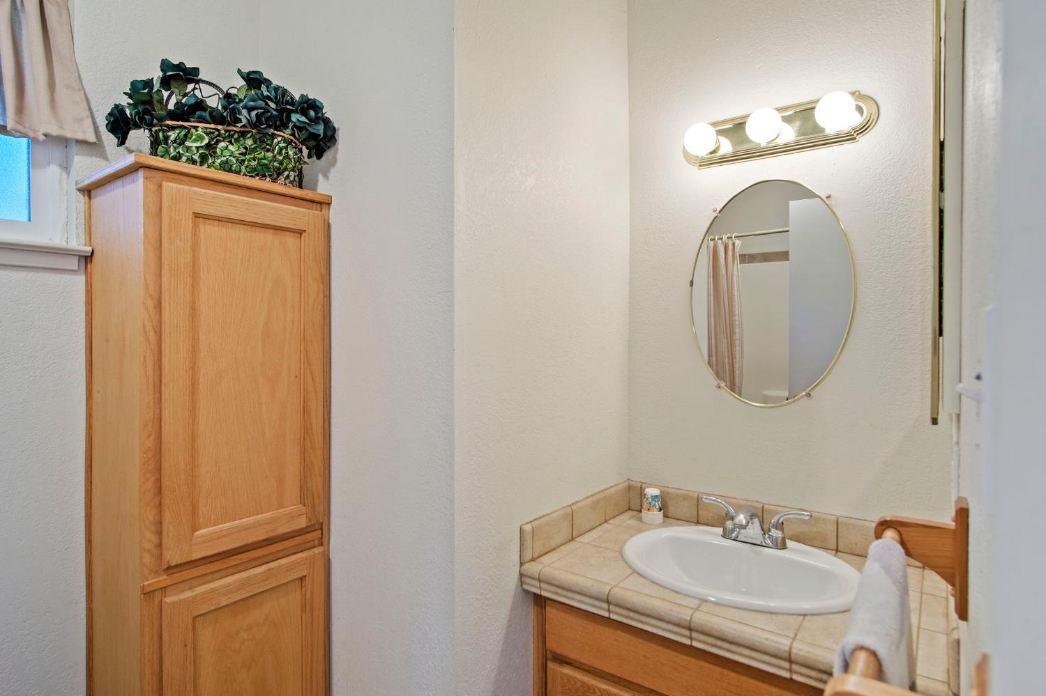 825 Wetherbee Avenue Manteca, CA 95337 - Photo 8 of 22 a bathroom with a sink and a mirror