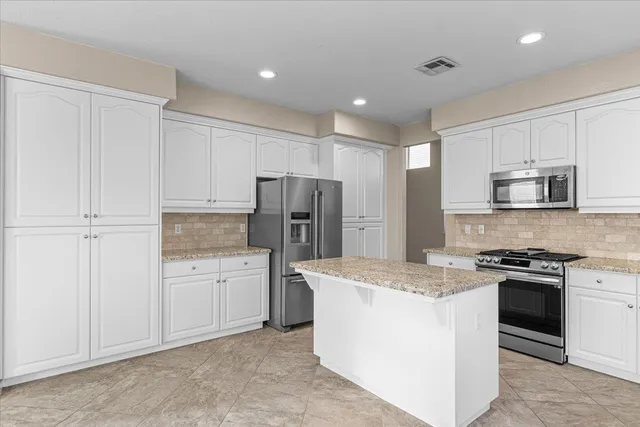 a kitchen with stainless steel appliances granite countertop white cabinets and window