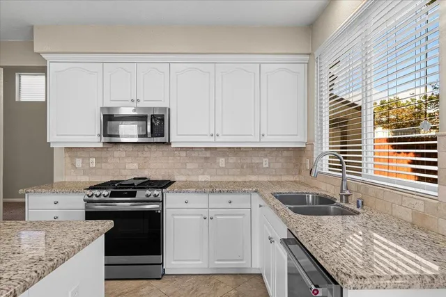 a kitchen with stainless steel appliances granite countertop a refrigerator a oven and a stove