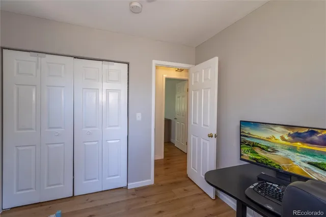an empty room with wooden floor lounge chair and windows