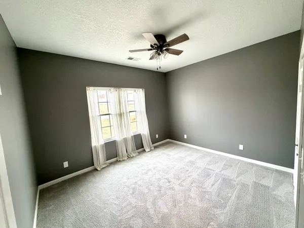 an empty room with windows and fan