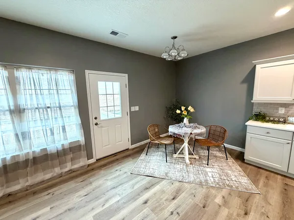a dining room with wooden floor a chandelier a wooden table and chairs