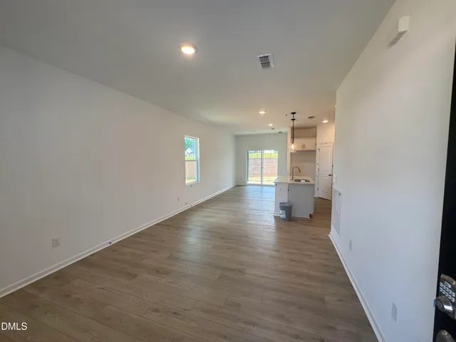 a view of a hallway with wooden floor and a kitchen