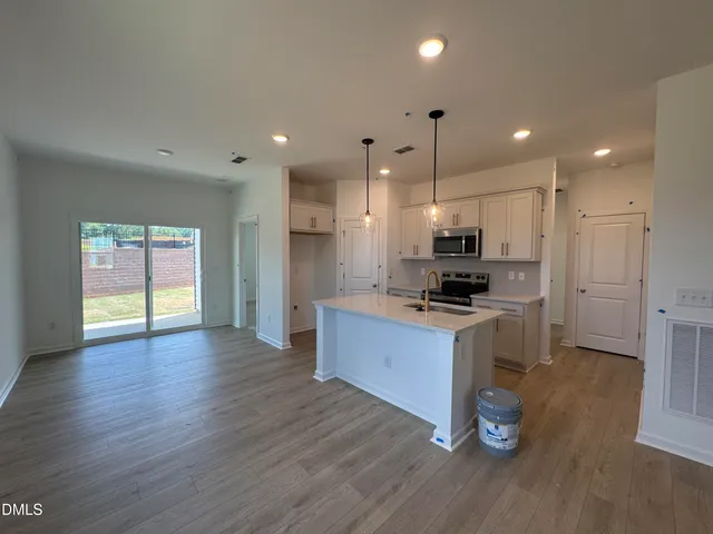 a kitchen with stainless steel appliances kitchen island granite countertop a stove a refrigerator a sink a microwave oven with wooden floor and cabinets