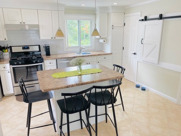 6 Saugus Avenue, Unit A Saugus, MA 01906 - Photo 9 of 26 a kitchen with stainless steel appliances kitchen island a table chairs in it and wooden floors