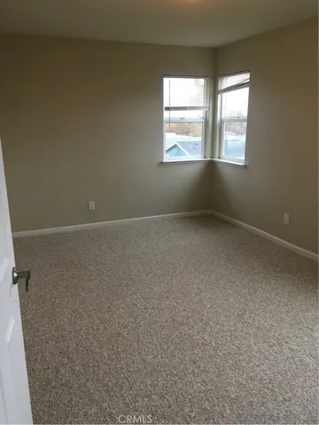 a view of an empty room with wooden floor and a fireplace