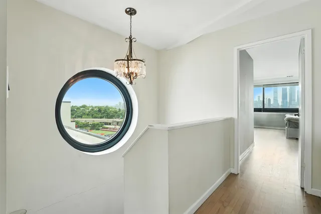 a view of a hallway with wooden floor and a chandelier