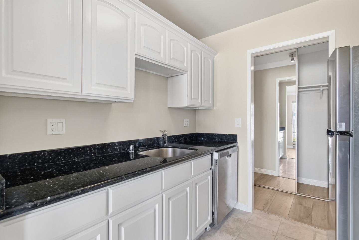8 Commodore Drive, Unit C457 Emeryville, CA 94608 - Photo 14 of 48 a kitchen with granite countertop white cabinets and black appliances