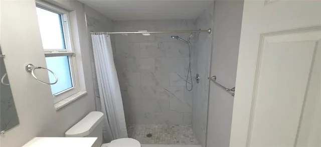 a bathroom with a shower a toilet and a window