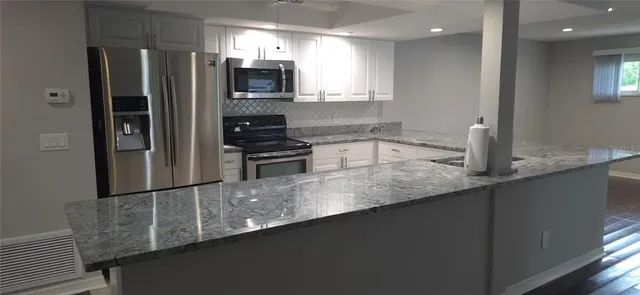 a kitchen with stainless steel appliances granite countertop a refrigerator a sink and a stove