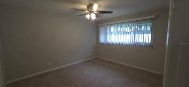 an empty room with a window and a fan