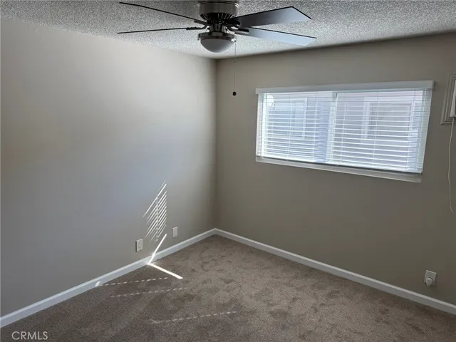 an empty room with a ceiling fan and window