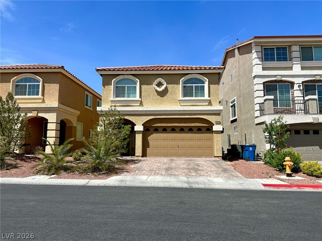 A terracotta-tiled roof crowns this residence, featuring a paver driveway and desert-friendly landscaping.