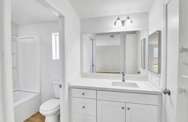 a bathroom with a toilet a sink a mirror and vanity