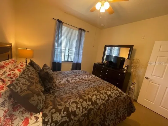 a bed sitting in a bedroom next to a window with pc on dresser