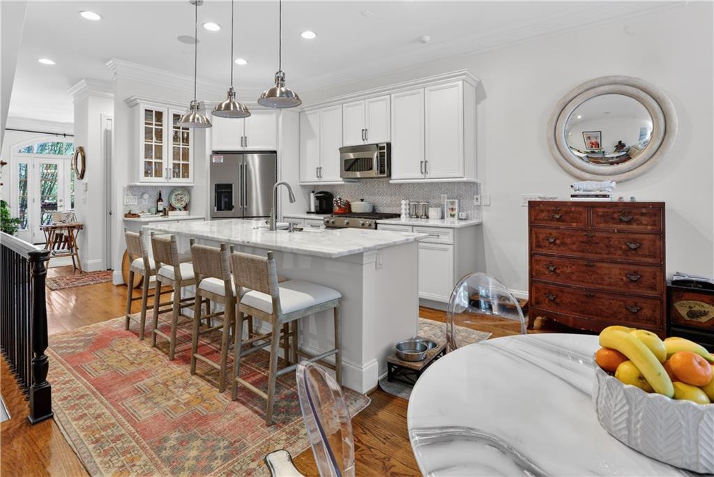 3552 Roswell Road Northwest Atlanta, GA 30305 - Photo 11 of 32 a kitchen with stainless steel appliances kitchen island granite countertop a sink a stove a dining table and chairs