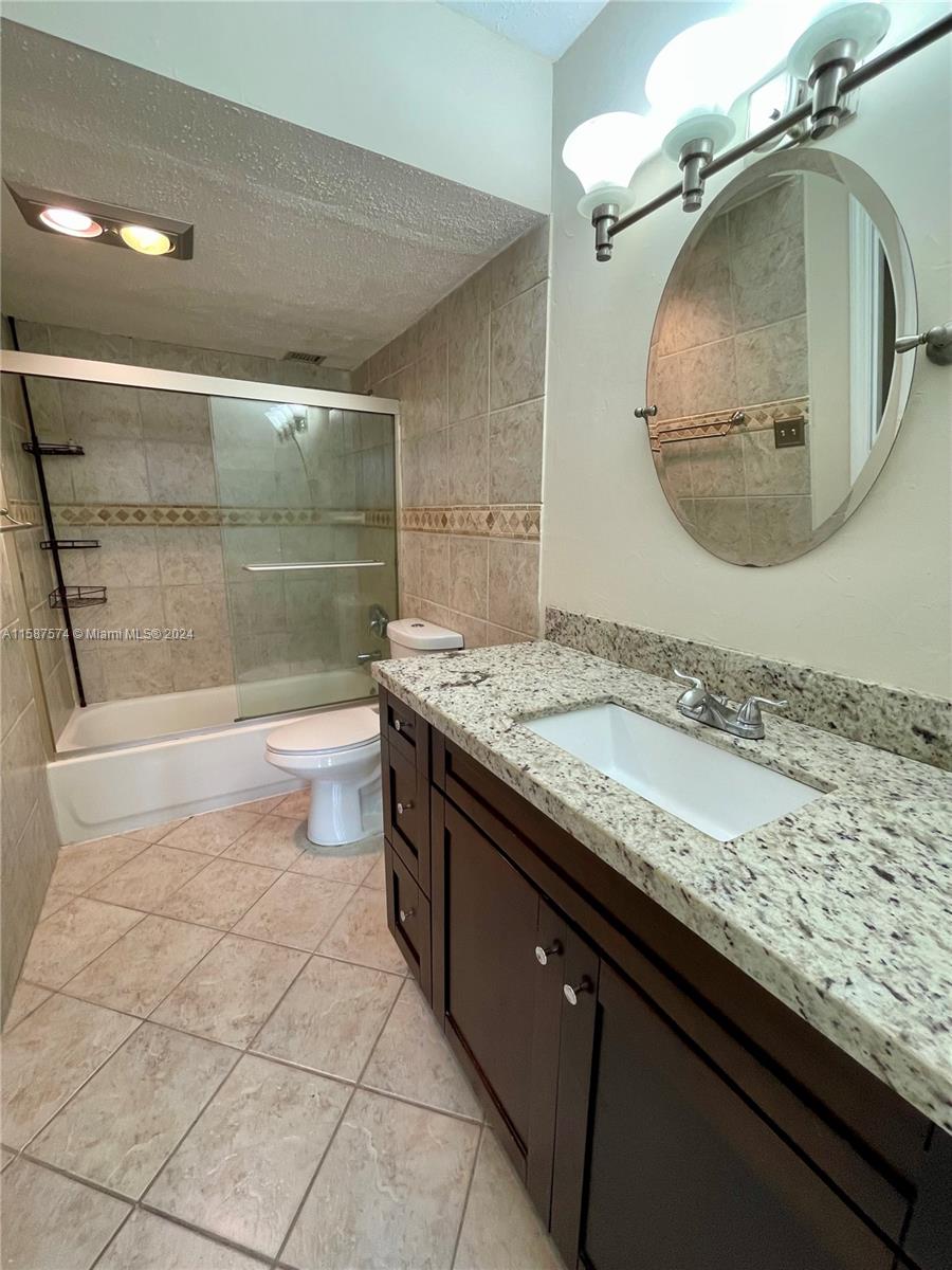 a bathroom with a granite countertop sink a mirror and shower