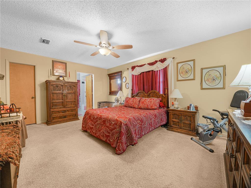 1100 Golden Bough Road Lake Wales, FL 33898 - Photo 25 of 49 a spacious bedroom with a bed a dresser and a chandelier