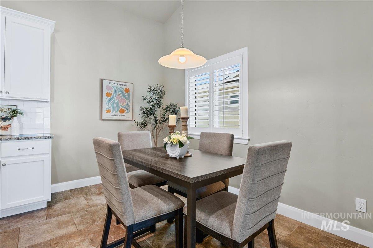 5850 West Rotherham Drive Eagle, ID 83616 - Photo 10 of 50 Vaulted dining area featuring plantation shutters, neutral wall tones, and a pendant light fixture