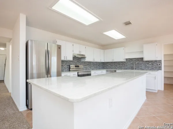 a kitchen with stainless steel appliances a refrigerator sink and white cabinets