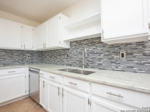 a kitchen with granite countertop white cabinets and white stainless steel appliances