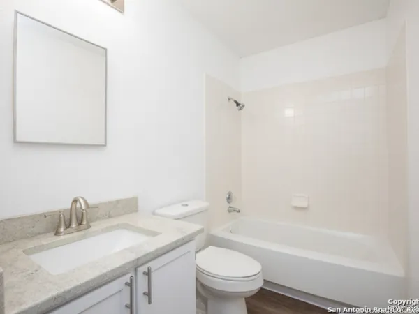 a bathroom with a granite countertop sink a toilet and bathtub