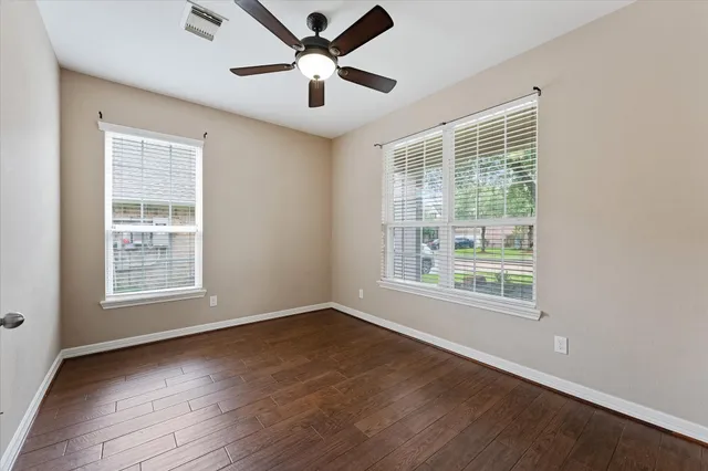 an empty room with windows and ceiling fan