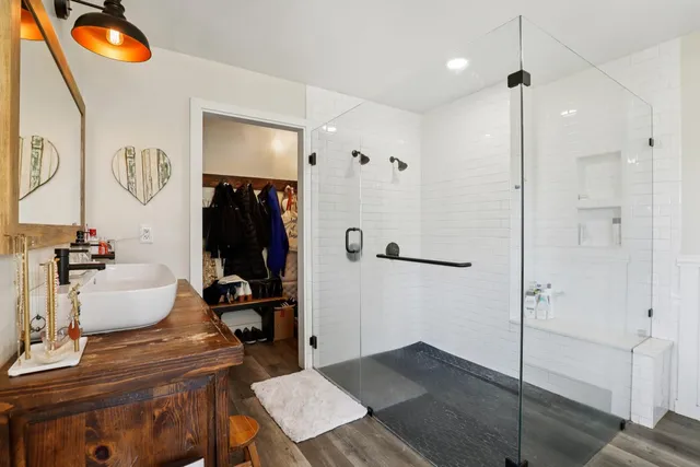 a bathroom with a granite countertop sink a mirror and shower