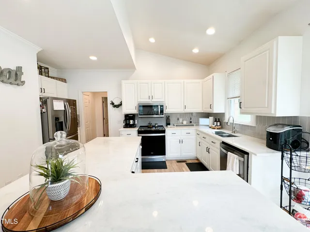a kitchen with stainless steel appliances kitchen island granite countertop a stove top oven a sink and a refrigerator