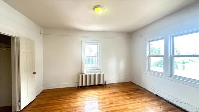 a view of an empty room with window and wooden floor