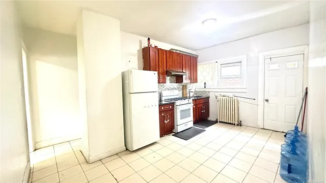 a kitchen with a refrigerator a stove top oven and white cabinets