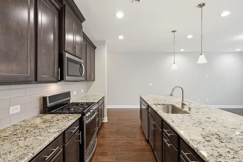 a kitchen with stainless steel appliances granite countertop a sink a stove top oven and refrigerator