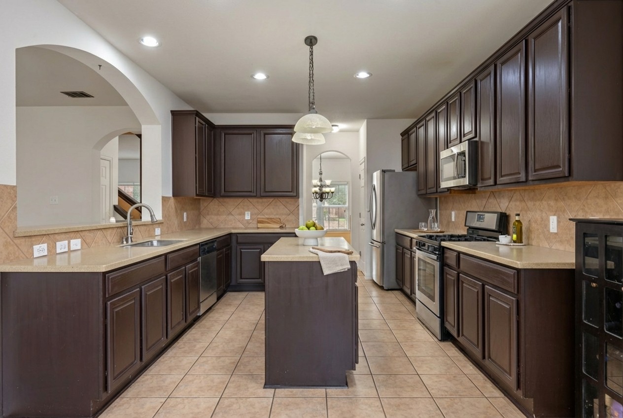2415 Elkhorn Ranch Road Leander, TX 78641 - Photo 7 of 39 a kitchen with a sink stove and wooden cabinets