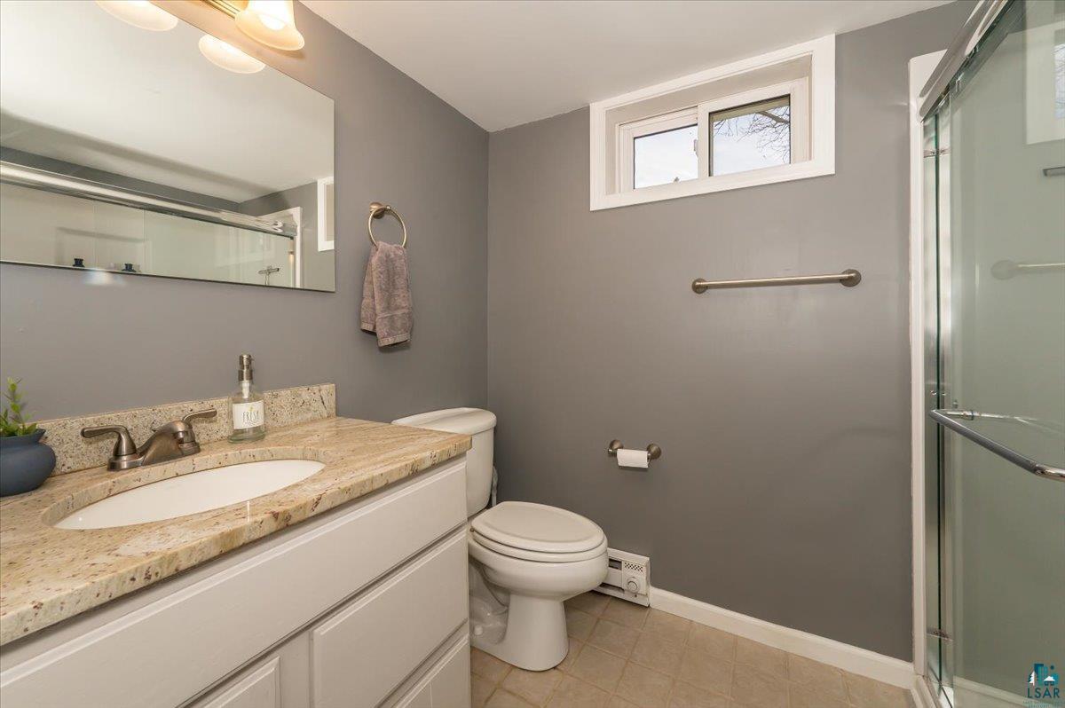 606 Maple Bend Drive Duluth, MN 55811 - Photo 19 of 30 3/4 bath with toilet, tile patterned floors, a shower with shower door, and vanity