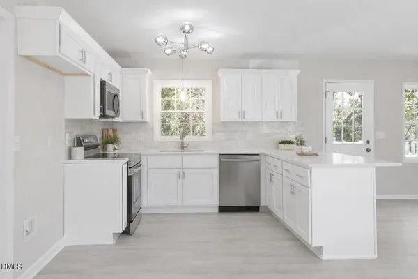 a kitchen that has a lot of white cabinets and stainless steel appliances