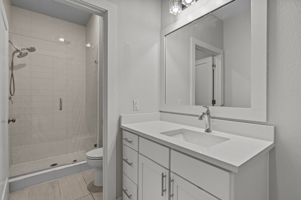 2827 Manor Road, Unit 2201 Austin, TX 78722 - Photo 30 of 40 Bathroom vanity featuring a quartz-finish countertop and integrated sink, framed mirror, and brushed nickel hardware