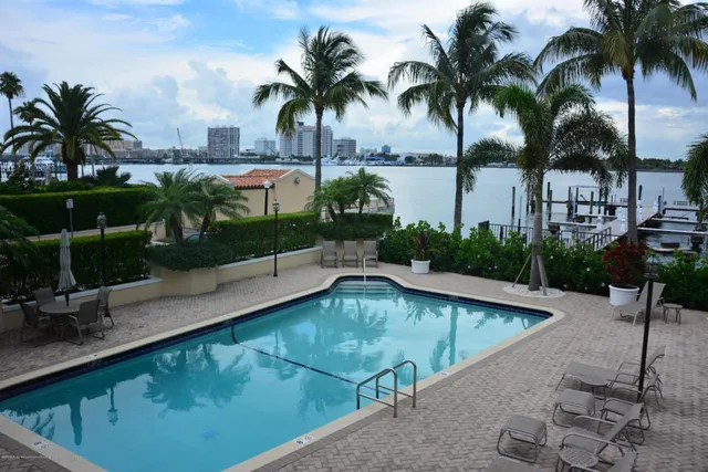 a view of a swimming pool with a patio and palm trees