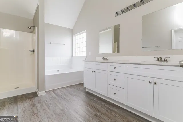 a spacious bathroom with double vanity a mirror and a bathtub