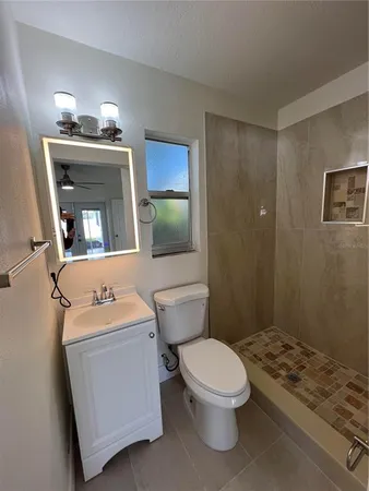 an empty room with wooden floor a ceiling fan and a window