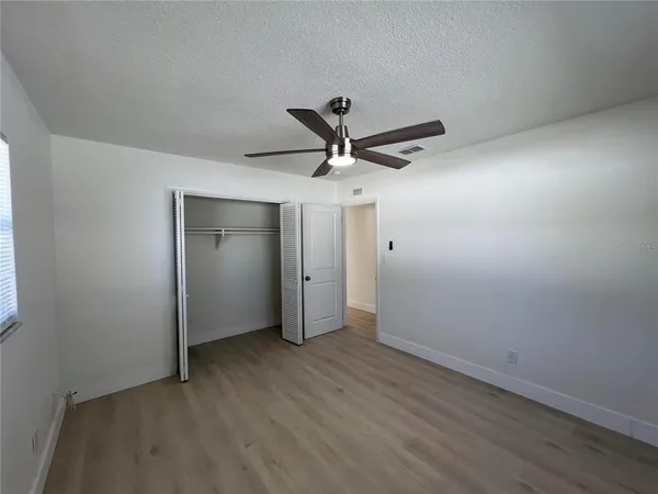 a view of empty room with wooden floor and fan