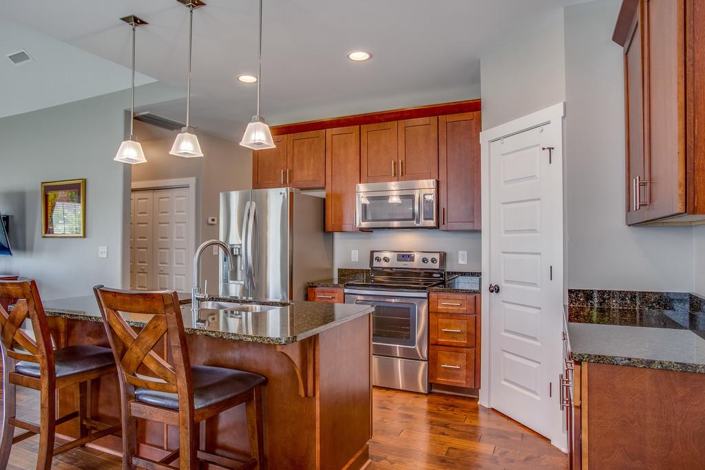 5012 Geranium Drive Spring Hill, TN 37174 - Photo 8 of 26 a kitchen with stainless steel appliances granite countertop a refrigerator a stove top oven a sink a dining table and chairs with wooden floor