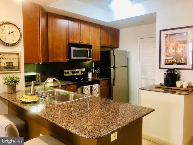 a kitchen with kitchen island granite countertop a sink stove and refrigerator