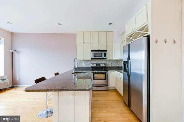 a kitchen with stainless steel appliances granite countertop a refrigerator a stove and a sink