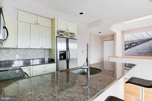 a kitchen with stainless steel appliances granite countertop a sink and a refrigerator