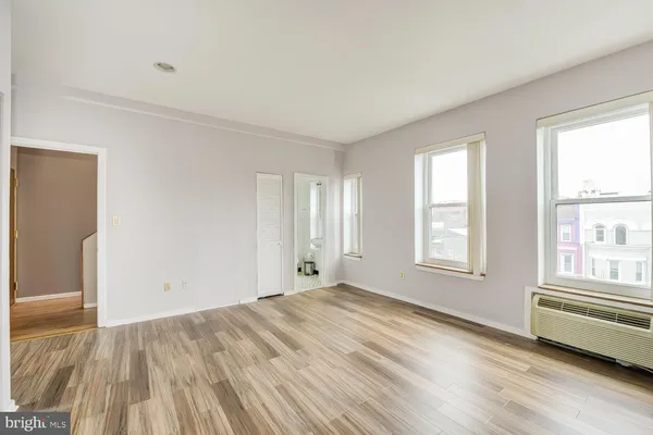 an empty room with wooden floor and windows